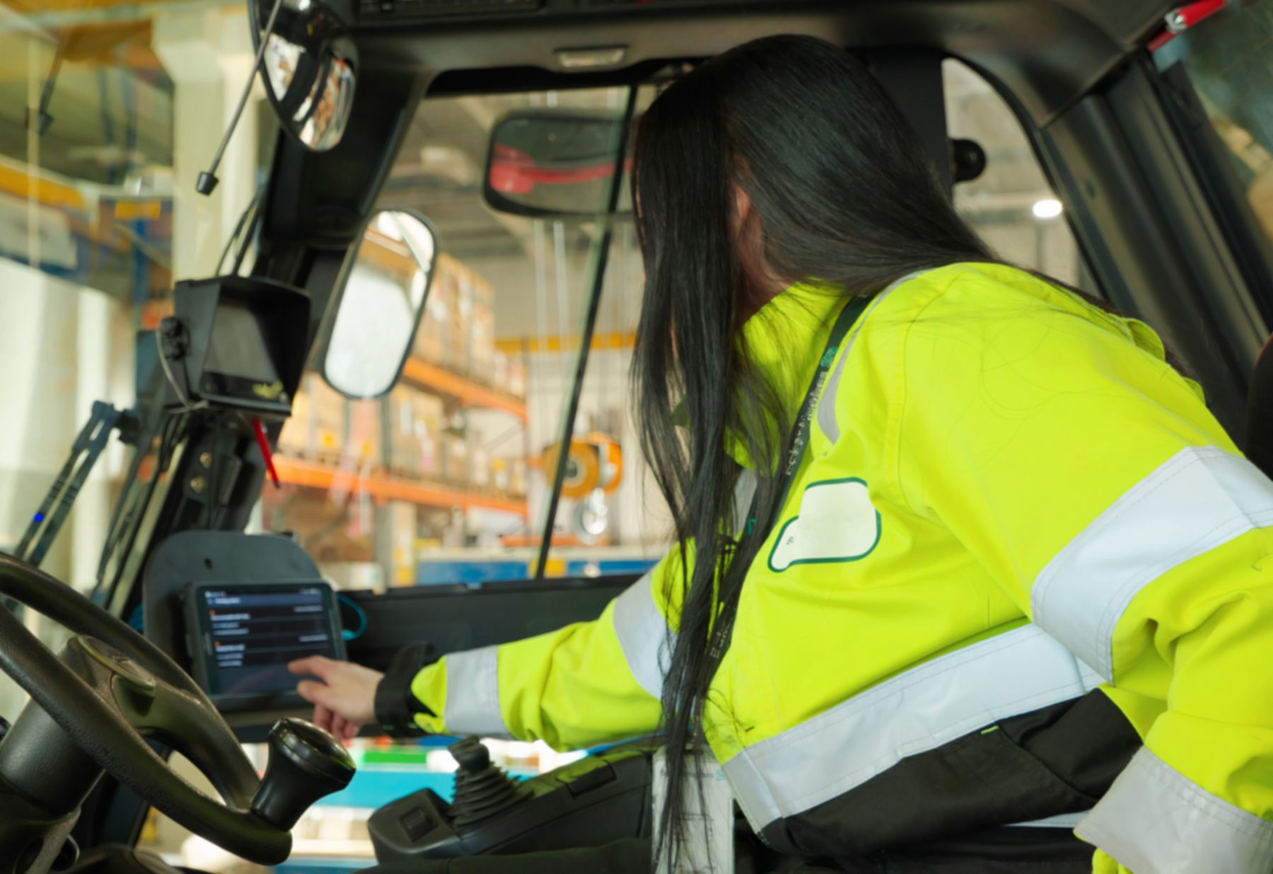 Forklift operator in a hi-vis jacket tapping a tablet mounted in the cab, EZYardService in daily use